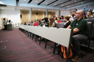 Parents and carers and children in Fenland sat in a university lecture facing front.
